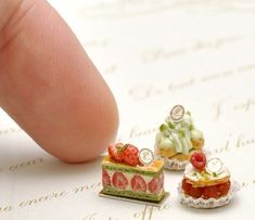 three miniature cakes sitting on top of a piece of paper next to a fingernail