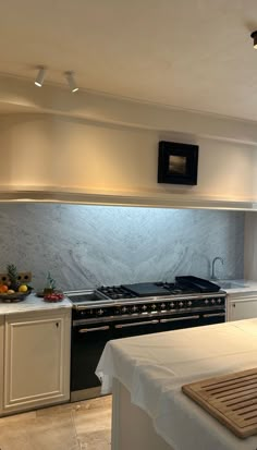 a kitchen with an oven, sink and counter tops in white marbled finish on the walls