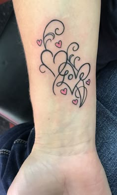 a woman's wrist tattoo with hearts and swirls in the shape of a heart