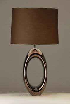 a lamp that is on top of a table with a brown shade over the base