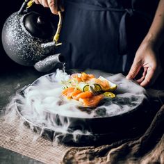 a person pouring tea on top of a plate with salmons and asparagus