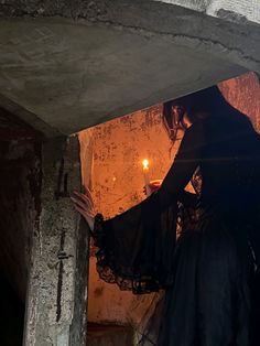 a woman dressed in black holding a candle