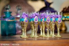 there are many wine glasses with purple and blue decorations on the top one is empty