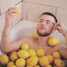 a man sitting in a bath filled with lemons