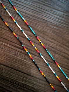 multicolored beaded necklaces sitting on top of a wooden table