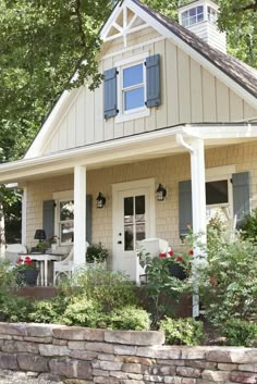 a white house with blue shutters on the front and side windows, surrounded by greenery