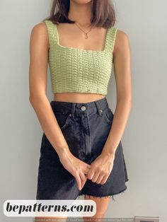 a woman wearing a green crop top and denim skirt with her hands in her pockets