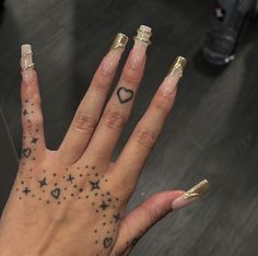 a woman's hand with tattoos on her fingers and two finger rings in the shape of stars