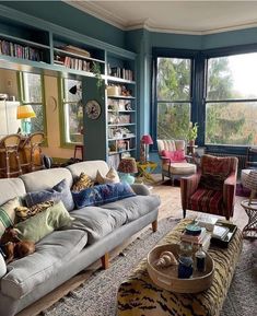 a living room filled with lots of furniture and bookshelves next to large windows