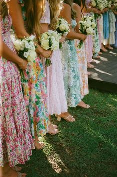 a group of women standing next to each other holding white and pink flowers in their hands