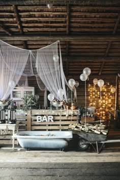 an old fashioned bar with balloons and lights on the ceiling, in a rustic setting