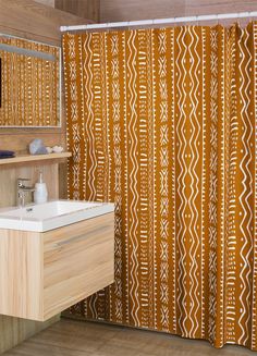 an orange and white shower curtain in a bathroom next to a sink with a mirror