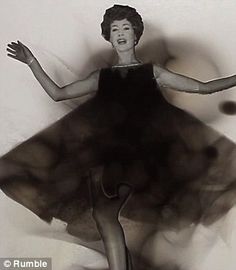 a black and white photo of a woman in a dress with her hands out to the side