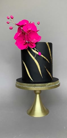 a black and gold cake with pink flowers on top