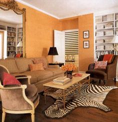 a living room filled with furniture and a zebra rug on top of a hard wood floor