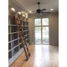 a ladder leaning against the wall in an empty room with shelves and a ceiling fan