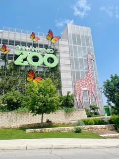 the entrance to an animal zoo with a giraffe and butterflies on it