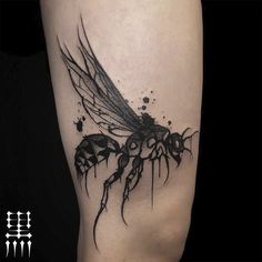 a black and white photo of a bee tattoo on the right thigh, with an insect in it's legs