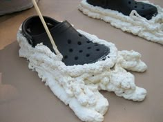 a pair of black and white crochet shoes on top of a table with a wooden stick