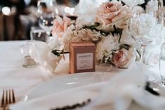 the table is set with white and pink flowers, silverware, and wine glasses