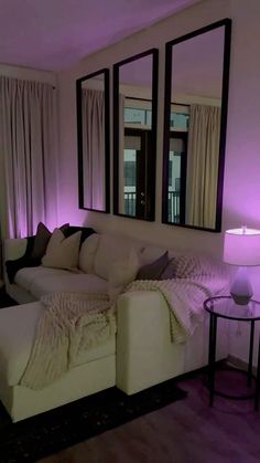 a living room with white couches and mirrors on the wall above them, all lit up by purple lighting