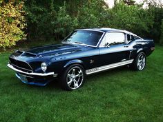 an old mustang muscle car parked in the grass