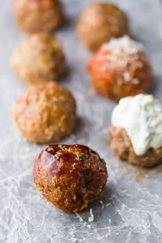 some meatballs are sitting on wax paper and covered in sauces or sour cream