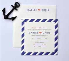 an anchor is on the table next to two wedding stationery cards, one with blue and white stripes