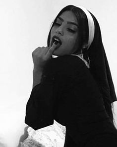 a woman with headphones on her ears is eating something while wearing a nun outfit