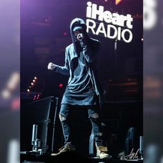 a man standing on top of a stage wearing a hoodie and holding a microphone