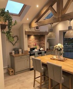 an open kitchen and dining room area with wood flooring, exposed beams and skylights