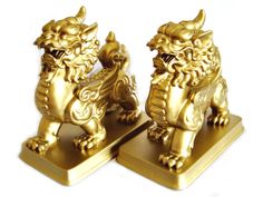 two golden foo foo statues sitting side by side on top of each other in front of a white background