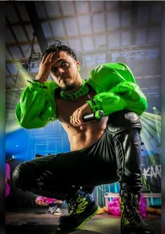 a shirtless man in black pants and neon green hoodie posing for the camera