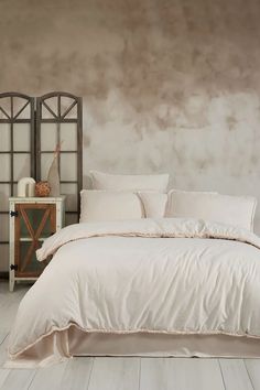 a bed with white sheets and pillows in a room