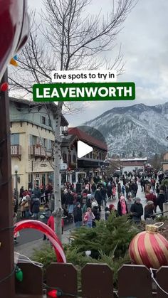 a crowd of people walking down a street next to tall buildings with christmas decorations on them