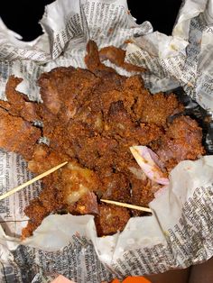 meat skewers sitting on top of newspaper with toothpicks stuck in them