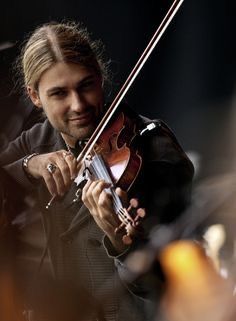 a man is playing the violin while others watch