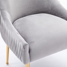 a grey velvet chair with wooden legs on a white background