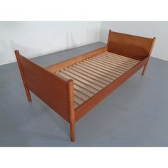 a wooden bed frame with slatted headboard and foot board on concrete floor