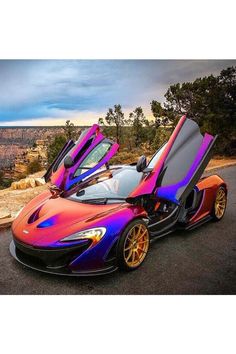 a colorful car parked on the side of a road with its doors open and it's hood up