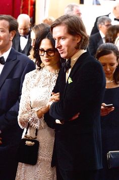 a man and woman standing next to each other in front of a group of people