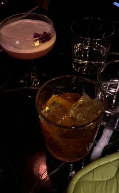 three different types of drinks sitting on a table next to each other with ice cubes in them