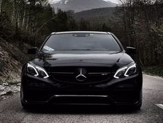 the front end of a black mercedes benz s - class car on a mountain road