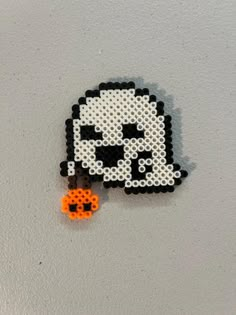 a pixel art brooch with an orange bead keychain hanging from it's side