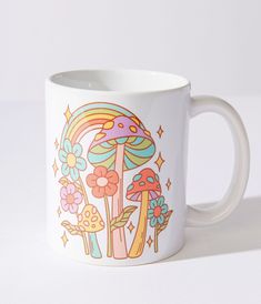 a white coffee mug with colorful mushrooms and flowers on the inside is sitting on a table