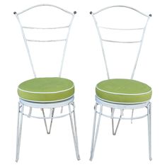 two white metal chairs with green cushions on each chair and one has a light green seat pad