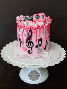 a pink cake with music notes and musical symbols on it, sitting on top of a table