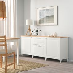 an empty room with white furniture and a painting on the wall above it's desk