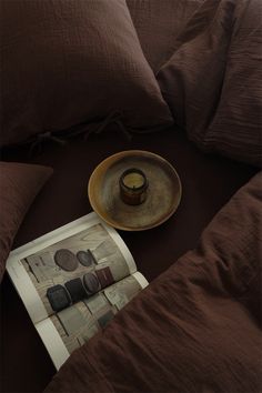 a plate with a candle on top of it next to some pillows and a cup