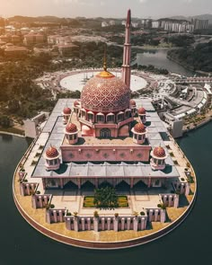 an aerial view of a mosque in the middle of a body of water with buildings around it